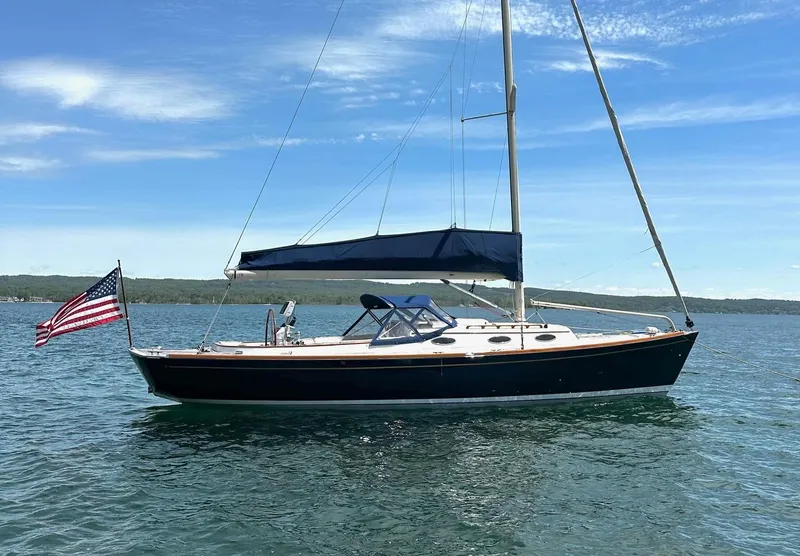 Slide: The Image of 2009 Alerion Express 38 sailboat on calm water, featuring an American flag and blue canopy. - 5