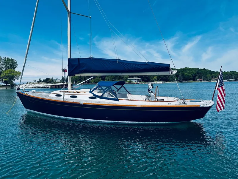Slide: The Image of 2009 Alerion Express 38 sailboat on calm water, blue hull, American flag, clear sky. - 9