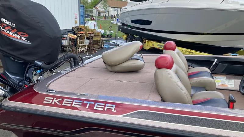 Slide: The Image of 2012 Skeeter FX20 bass boat with spacious deck and seating, parked in a suburban neighborhood. - 2
