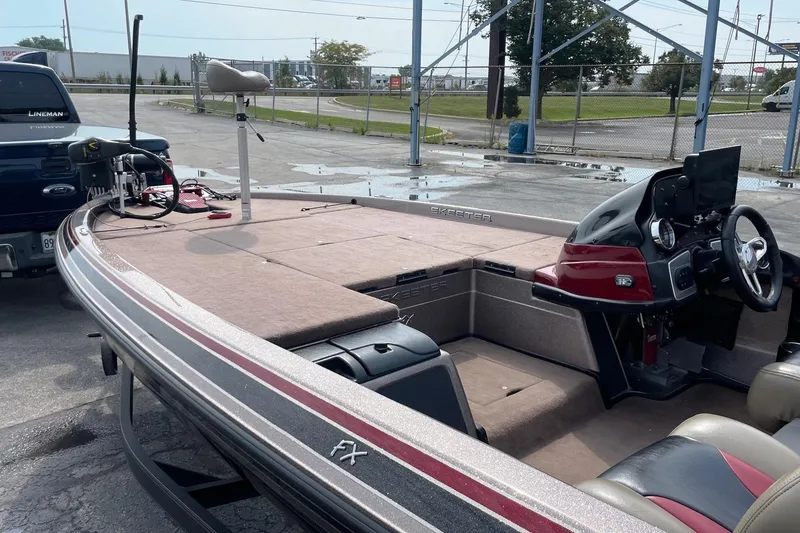 Slide: The Image of 2012 Skeeter FX20 bass boat with red accents, parked near a truck. - 21