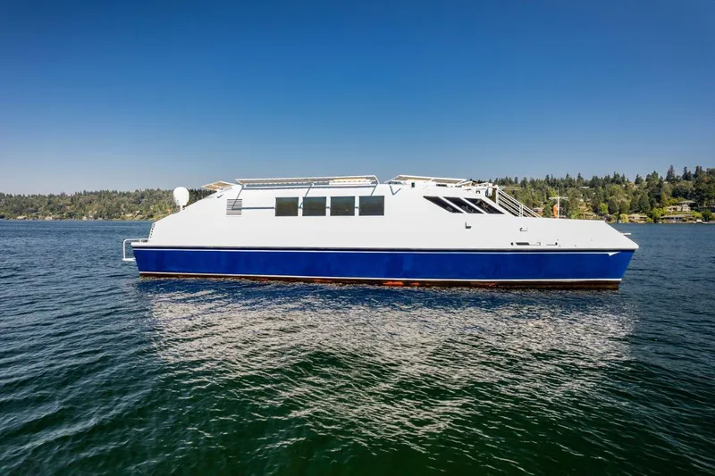 Slide: The Image of Dakota Creek 1999 catamaran, helicopter capable, on a serene lake with clear blue skies. - 14