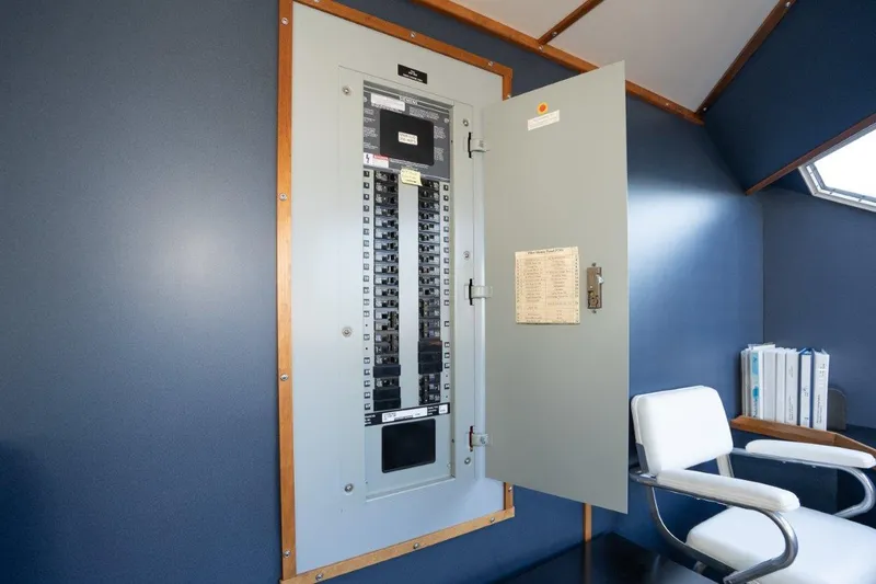 Slide: The Image of Electrical panel in a 1999 Dakota Creek Catamaran, open door, blue interior, white chair nearby. - 23
