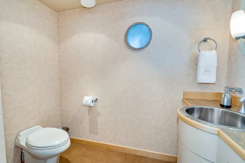Slide: The Image of Bathroom interior of 1999 Dakota Creek Catamaran, featuring toilet, sink, and porthole window. - 38