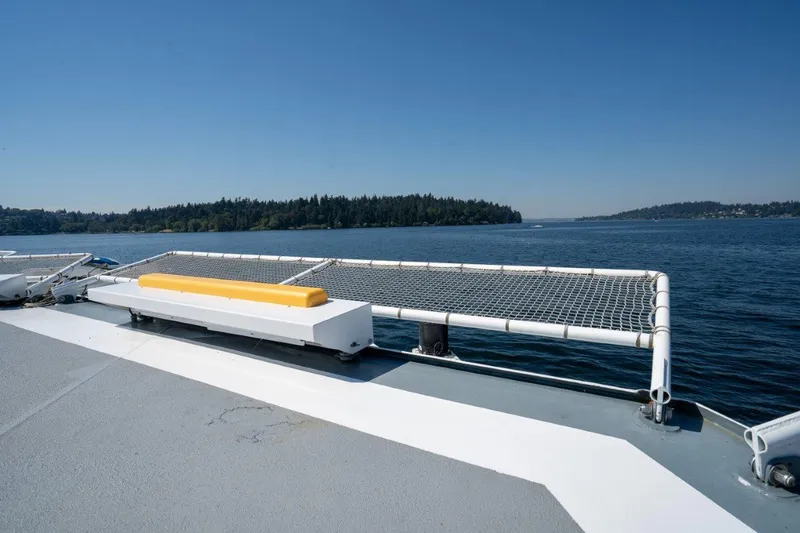 Slide: The Image of Catamaran deck with safety netting, overlooking calm waters and distant forested shoreline. - 45