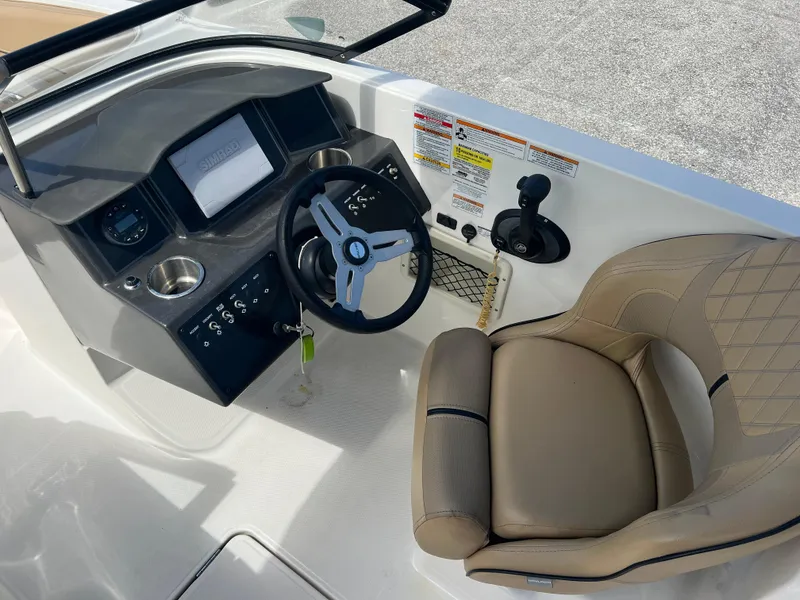 Slide: The Image of 2023 Bayliner VR6 boat cockpit with steering wheel, control panel, and beige captain's chair. - 15