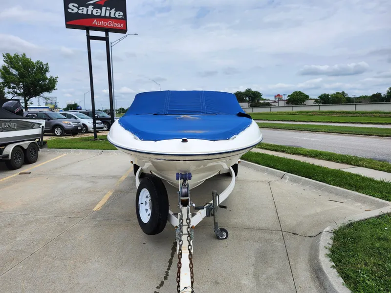 Slide: The Image of 2002 Bayliner 215 Capri boat on trailer with blue cover in parking lot. - 13
