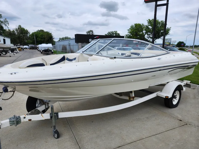 Slide: The Image of 2002 Bayliner 215 Capri boat on a trailer in a parking lot. - 2