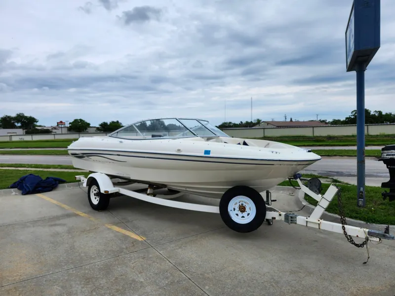 Slide: The Image of 2002 Bayliner 215 Capri boat on a trailer in a parking lot. - 6