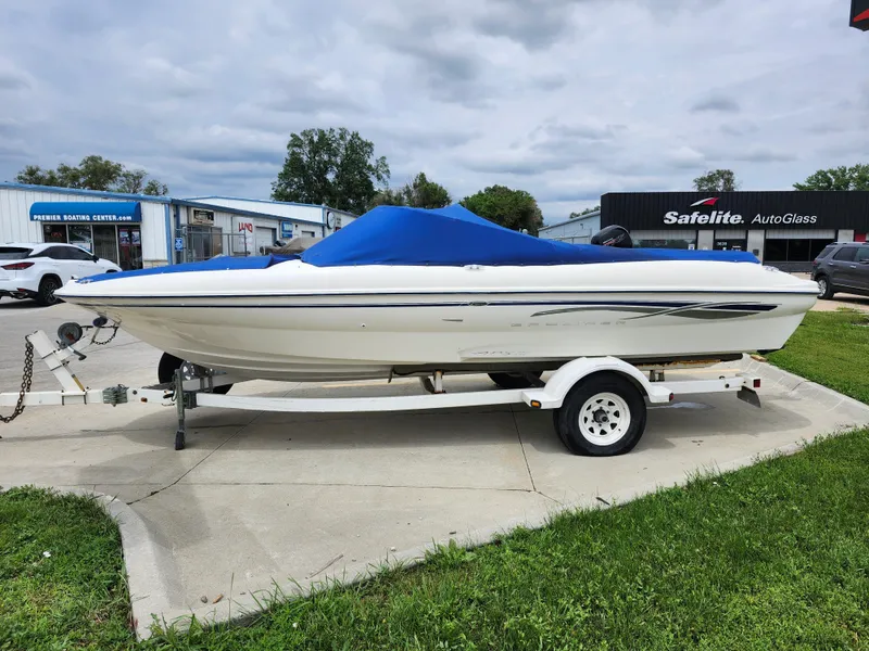Slide: The Image of 2002 Bayliner 215 Capri boat on trailer with blue cover in parking lot. - 9