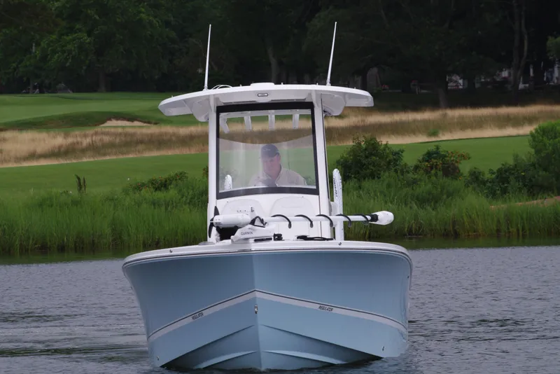 Slide: The Image of 2025 Regulator 24XO boat on calm water with lush greenery in the background. - 12