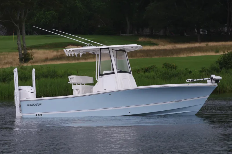 Slide: The Image of 2025 Regulator 24XO boat on calm water with lush green background. - 2