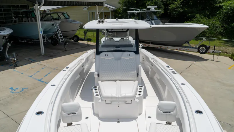 Slide: The Image of 2025 Fountain 38 TE boat with white seating and center console in a marina. - 11