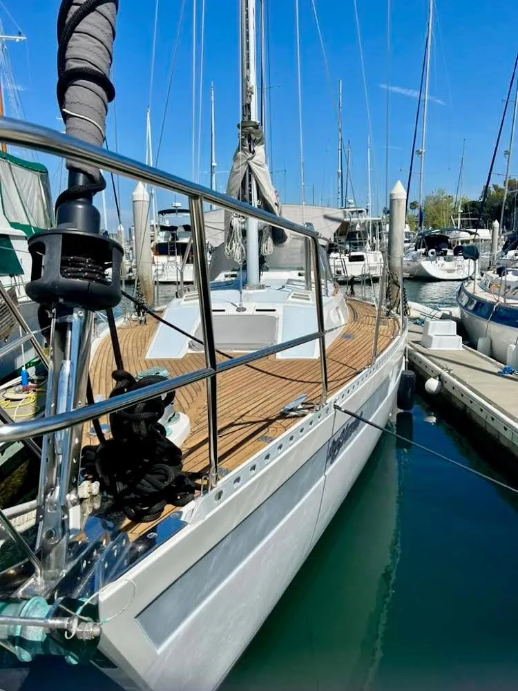 Slide: The Image of 1987 Norseman 400 sailboat docked in marina, showcasing sleek design and wooden deck. - 4