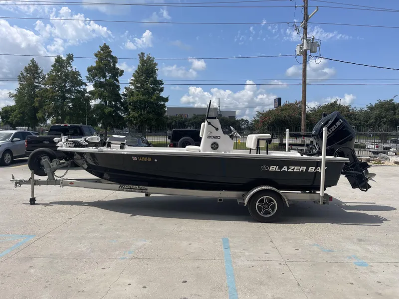 Slide: The Image of 2020 Blazer Bay boat on trailer with Suzuki outboard motor, parked outdoors. - 23