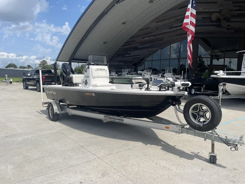 Slide: The Image of 2021 Blazer Bay boat on trailer outside a showroom with American flag. - 25