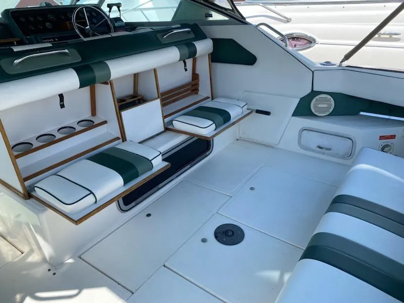 Slide: The Image of 1989 Sea Ray '30 Sundancer interior with green and white seating, cup holders, and steering wheel. - 2