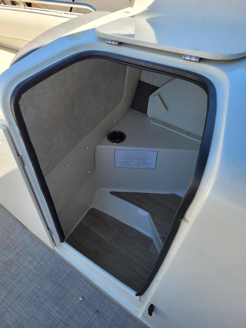 Slide: The Image of 2022 Stingray 212SC boat interior storage compartment with wood flooring. - 18