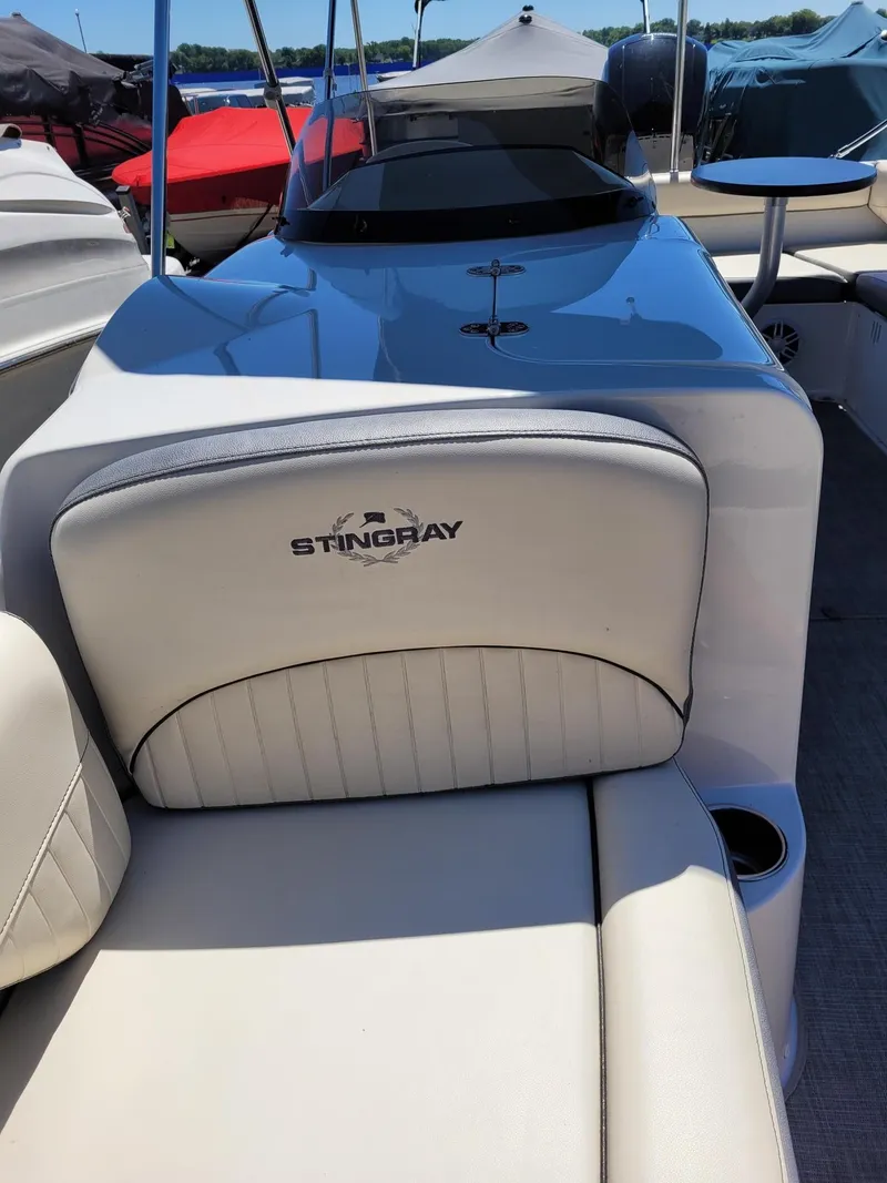 Slide: The Image of 2022 Stingray 212SC boat interior with white cushioned seating and cup holder. - 25