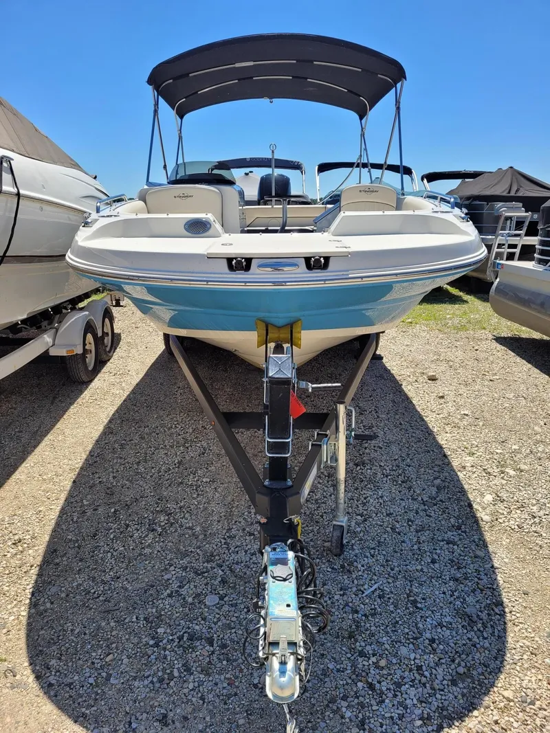 Slide: The Image of 2022 Stingray 212SC boat on trailer with canopy, parked outdoors. - 26