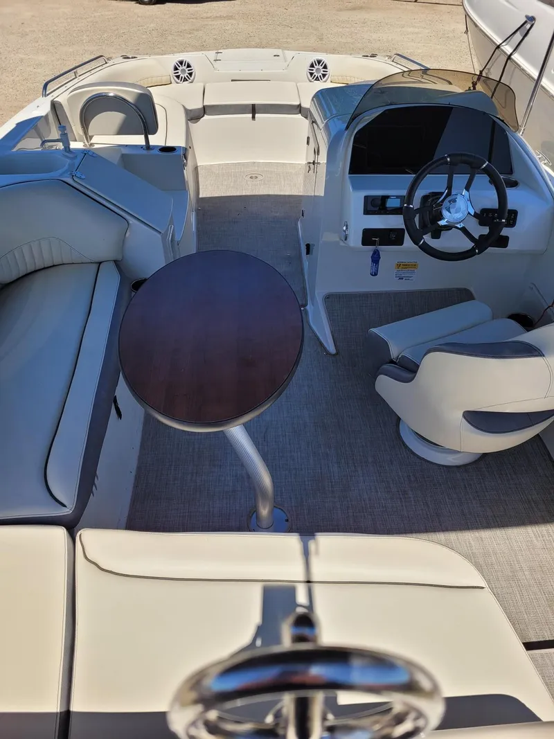 Slide: The Image of 2022 Stingray 212SC boat interior with seating, table, and steering console. - 5