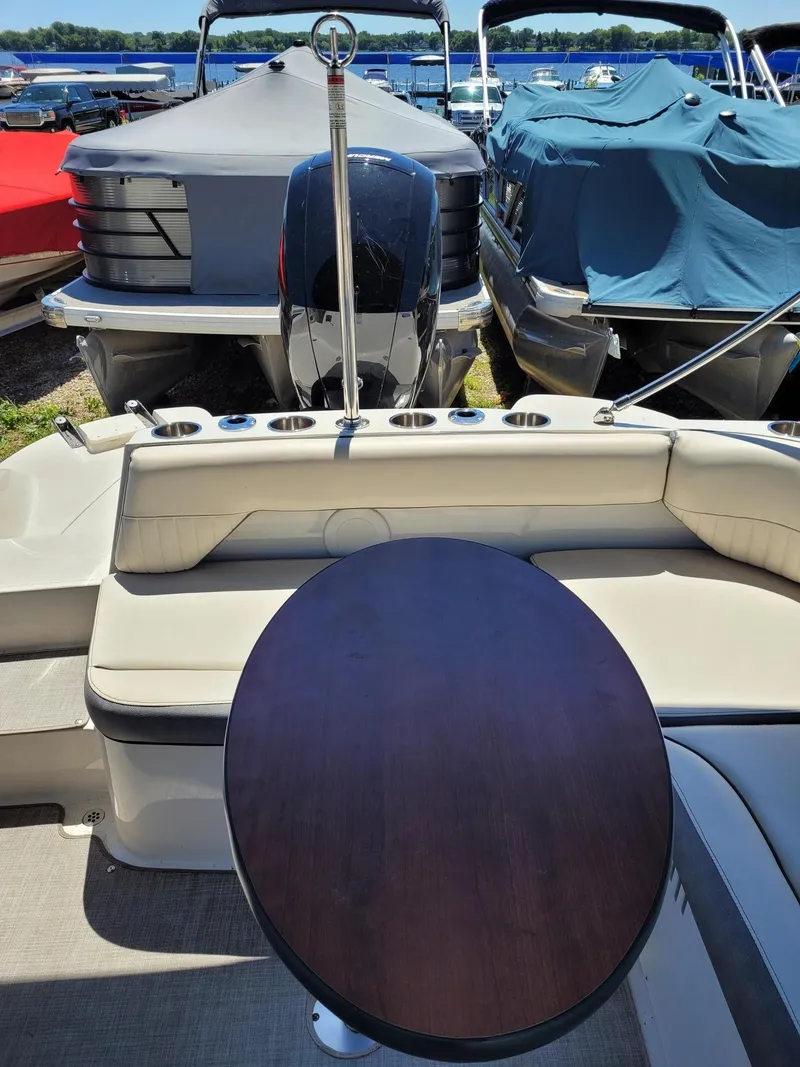 Slide: The Image of 2022 Stingray 212SC boat interior with table, docked among covered boats. - 7