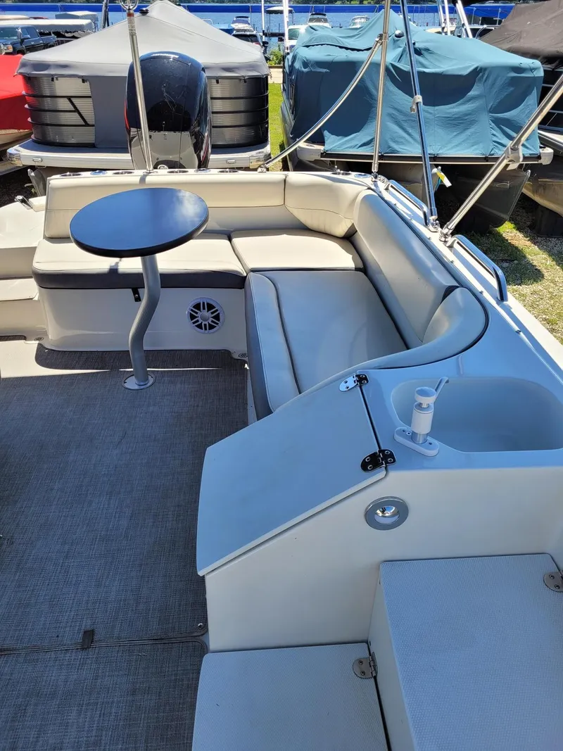 Slide: The Image of 2022 Stingray 212SC boat interior with seating, table, and covered boats in the background. - 9