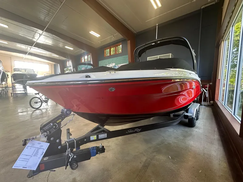 Slide: The Image of 2024 Sea Ray SPX 210 boat in showroom, red and white exterior, on trailer. - 2