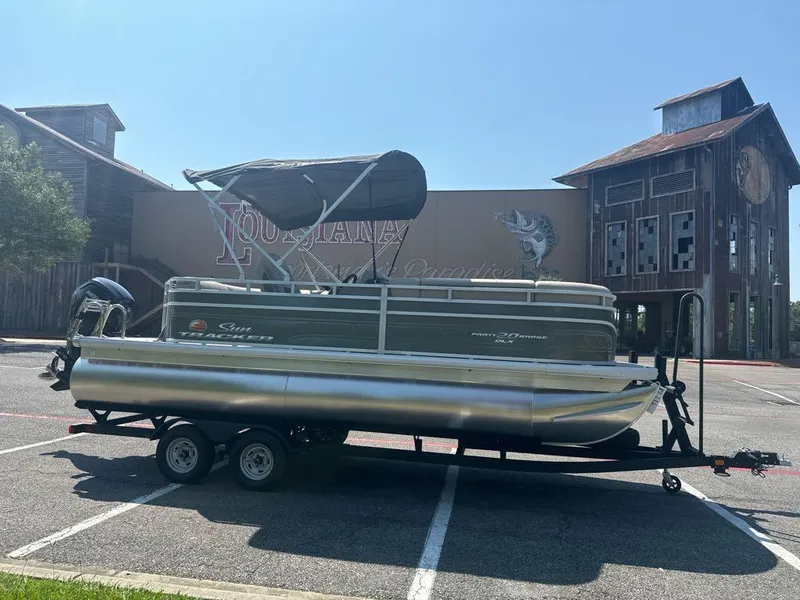 Slide: The Image of 2024 Sun Tracker Party Barge 20 DLX pontoon boat on trailer in parking lot. - 2