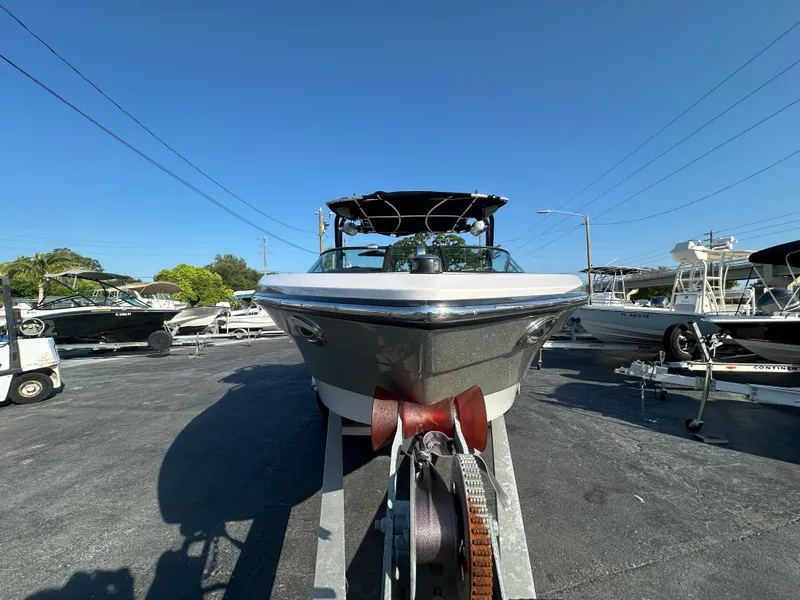 Slide: The Image of 2010 Nautique Super Air Nautique 230 boat on trailer in a marina. - 2