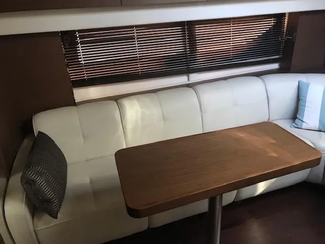 Slide: The Image of Interior seating area of 2013 Sea Ray 470 Sundancer yacht with white leather couch and wooden table. - 18