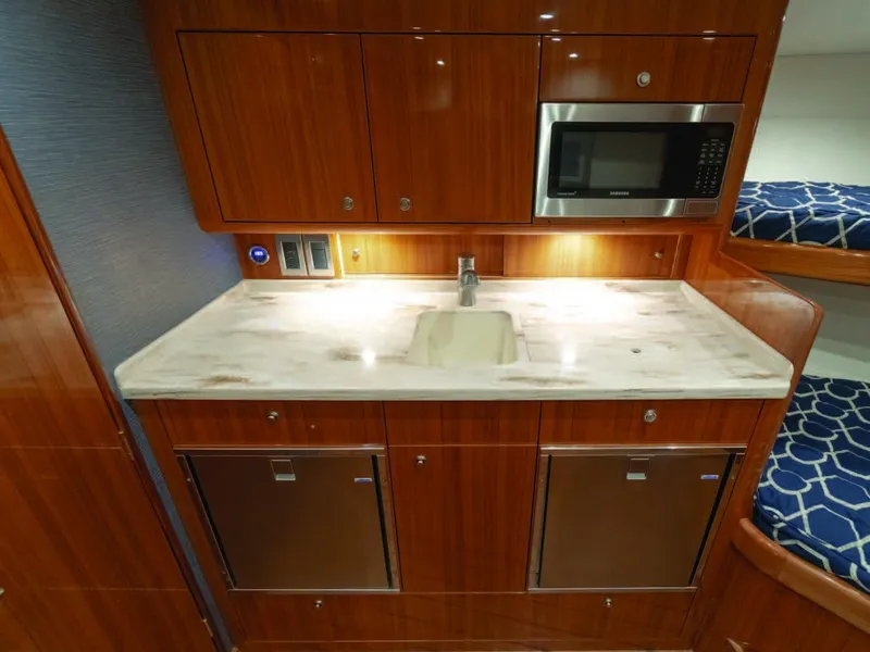 Slide: The Image of 2025 Viking 38 Open Billfish galley with sink, microwave, and storage cabinets. - 2