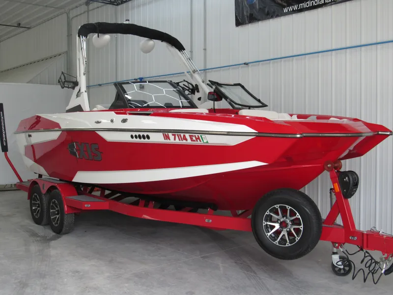 Slide: The Image of 2022 Axis A22 red and white boat on a matching red trailer in a garage. - 2
