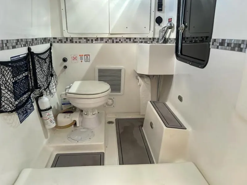 Slide: The Image of 2023 AMP Arth 333 boat interior bathroom with toilet, sink, and storage compartments. - 14