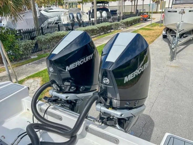 Slide: The Image of Dual Mercury outboard motors on AMP Arth 333 boat, 2023 model, docked near other boats. - 17