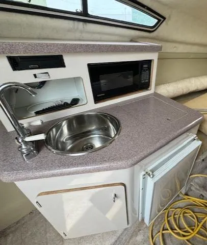 Slide: The Image of 1995 Regal 256 Commodore boat kitchenette with sink, microwave, and storage. - 32