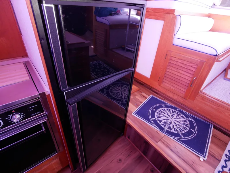 Slide: The Image of 1986 Silverton 40 Convertible kitchen area with black refrigerator and wooden cabinetry. - 30