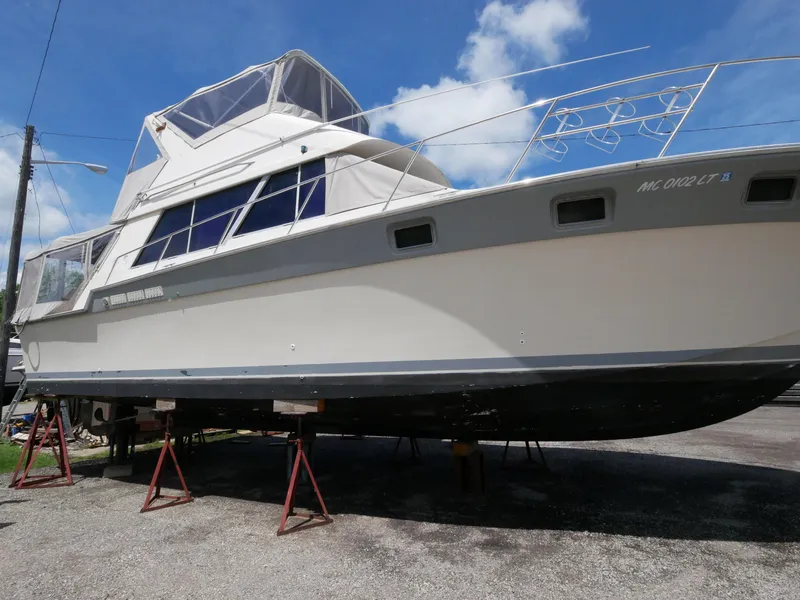 Slide: The Image of 1986 Silverton 40 Convertible boat on stands, side view, clear sky background. - 6