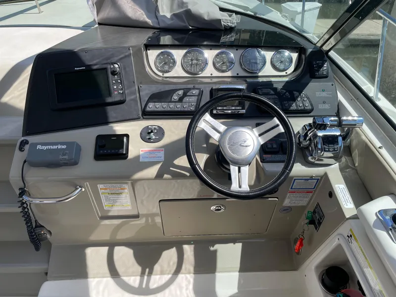 Slide: The Image of 2014 Sea Ray 370 Sundancer helm with steering wheel, gauges, and navigation equipment. - 24
