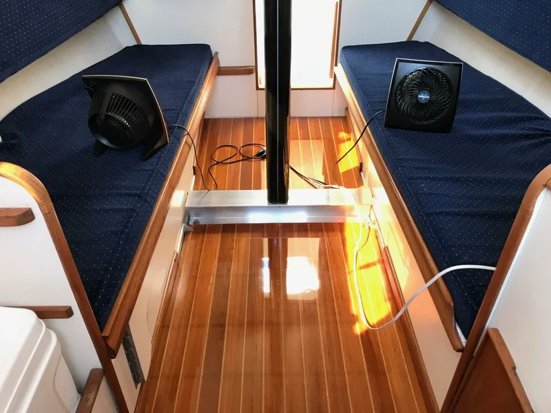 Slide: The Image of Interior of a 1980 Chrysler S-27 boat with wooden flooring and blue cushioned seating. - 16