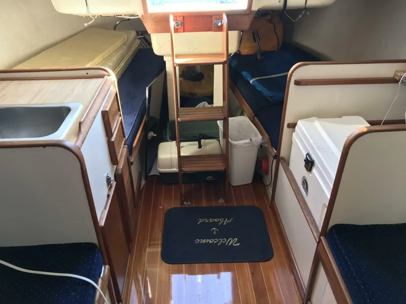 Slide: The Image of Interior of a 1980 Chrysler S-27 sailboat with wooden flooring and compact amenities. - 6