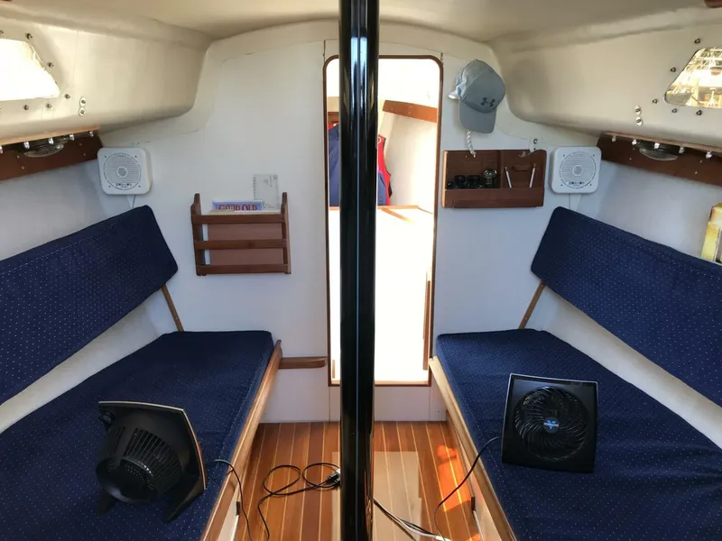 Slide: The Image of Interior of a 1980 Chrysler S-27 sailboat with blue seating and wooden flooring. - 7