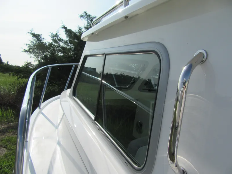 Slide: The Image of 2025 Parker 2420 Sport Cabin boat exterior with sleek windows and railing. - 13