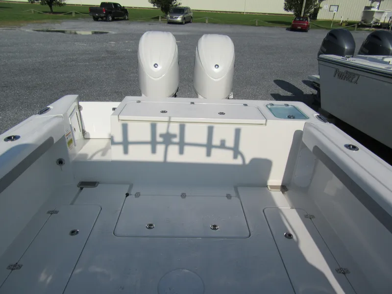 Slide: The Image of 2025 Parker 2420 Sport Cabin boat deck with dual engines in a parking lot. - 6