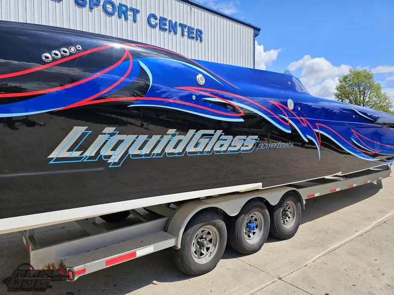 Slide: The Image of 2011 Catamaran Liquid Glass 41 on trailer, vibrant graphics, parked outside sport center. - 12