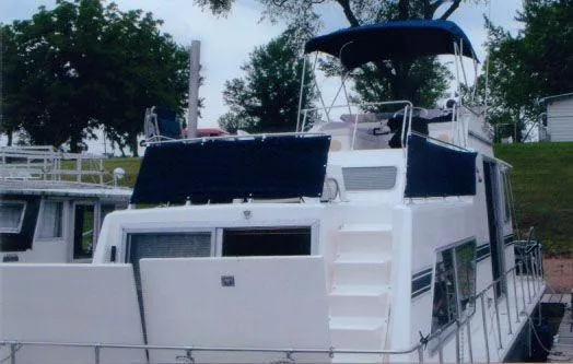 Slide: The Image of 1992 Holiday Mansion houseboat with blue canopy, docked near trees. - 14