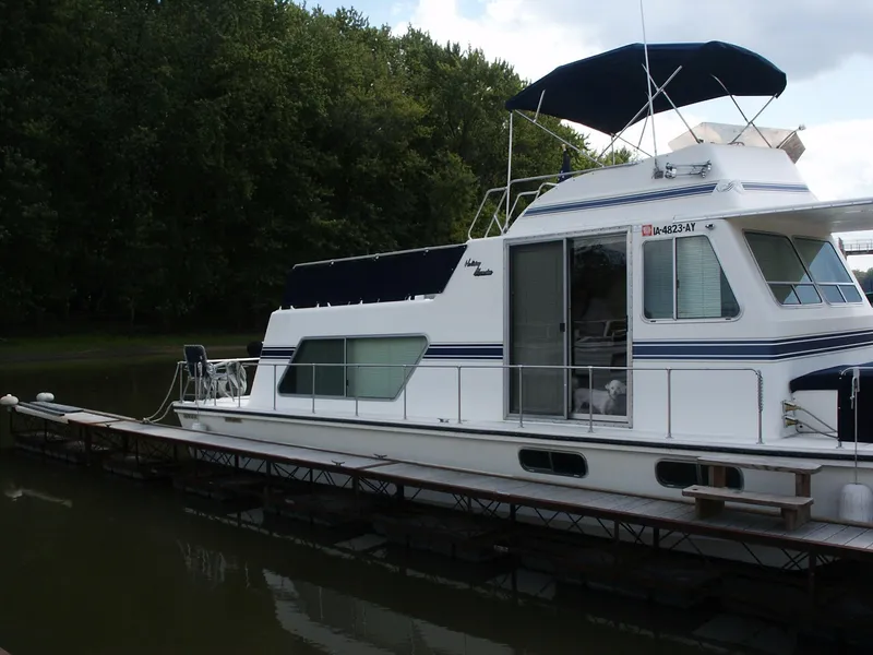 Slide: The Image of 1992 Holiday Mansion houseboat docked on a calm river, surrounded by lush greenery. - 20