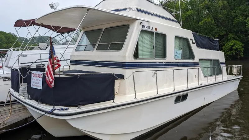 Slide: The Image of 1992 Holiday Mansion houseboat docked, for sale, with American flag and covered deck. - 23