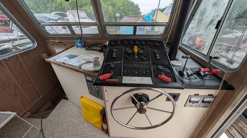 Slide: The Image of 1992 Holiday Mansion houseboat helm with steering wheel and control panel, docked near other boats. - 24