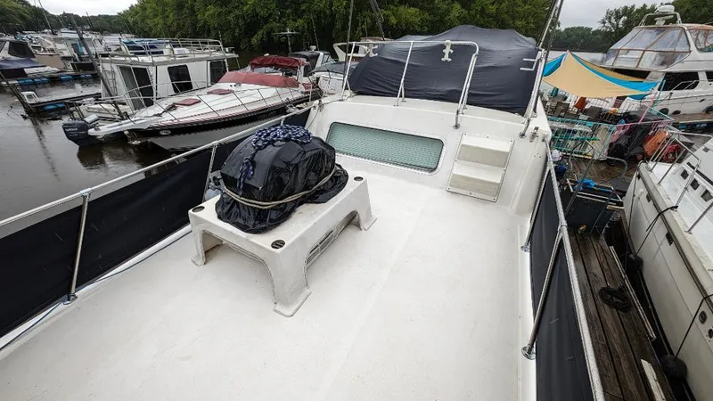 Slide: The Image of 1992 Holiday Mansion houseboat deck with covered equipment, docked among other boats. - 26