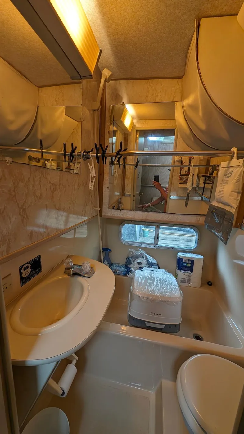 Slide: The Image of 1992 Holiday Mansion houseboat bathroom with sink, toilet, and storage cabinets. - 29